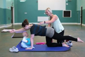 Exercising at a pilates class with baby watching.