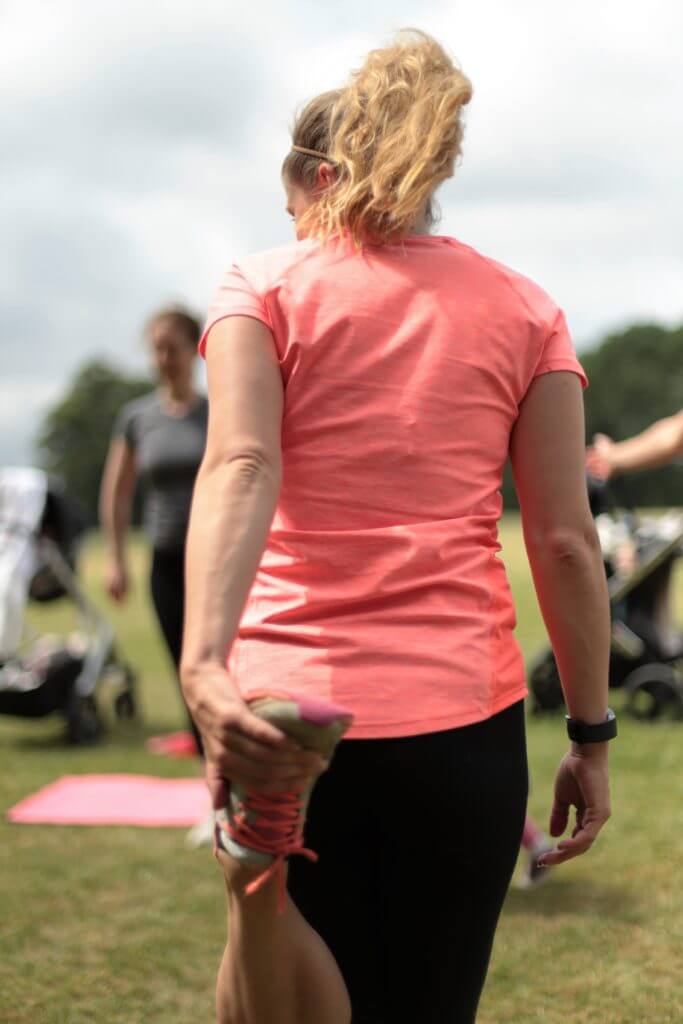 back of a lady doing a hamstring stretch.